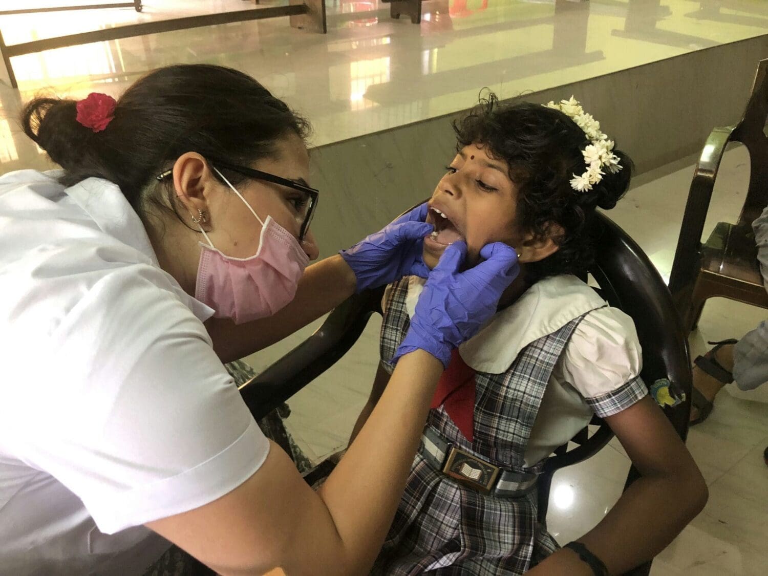Volunteer checking students teeth in school